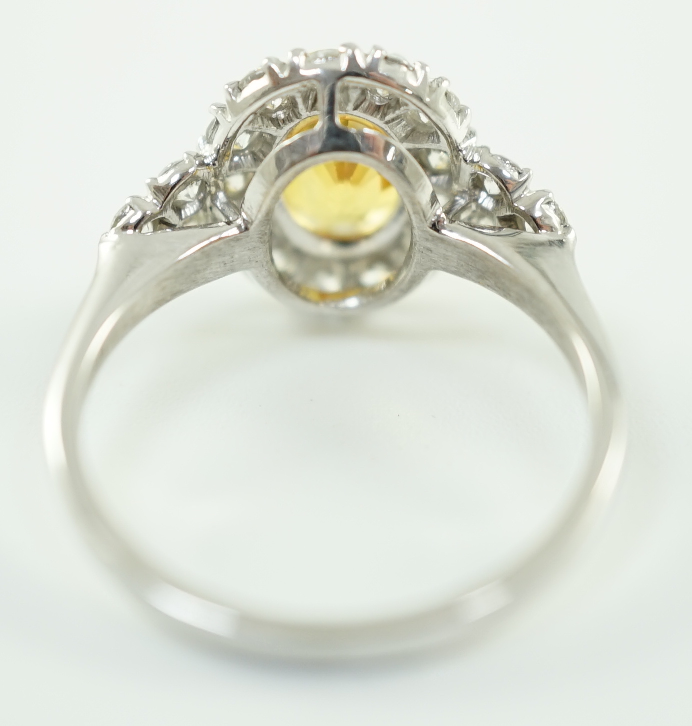 A modern 18ct white gold and single oval cut yellow sapphire set ring